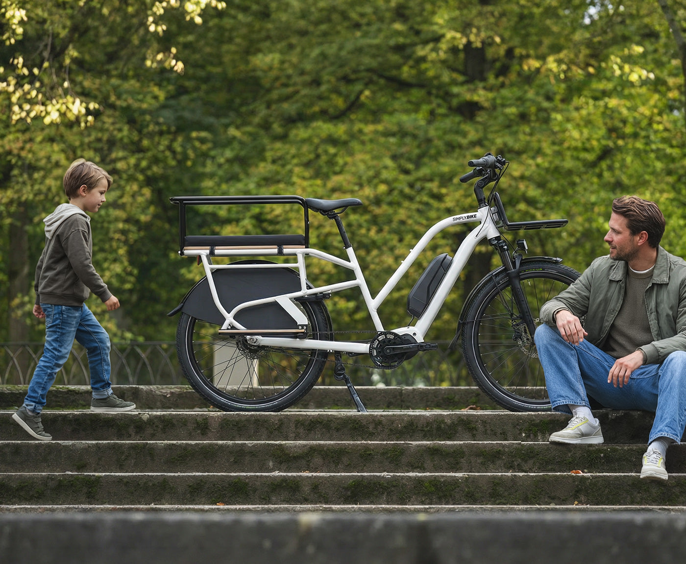 Ein Mann und ein Kind bei einer Pause neben einem Simply.Lift EP6 Longtail E-Lastenrad mit montiertem Sicherheits-Handlauf auf einer Steintreppe im Freien.