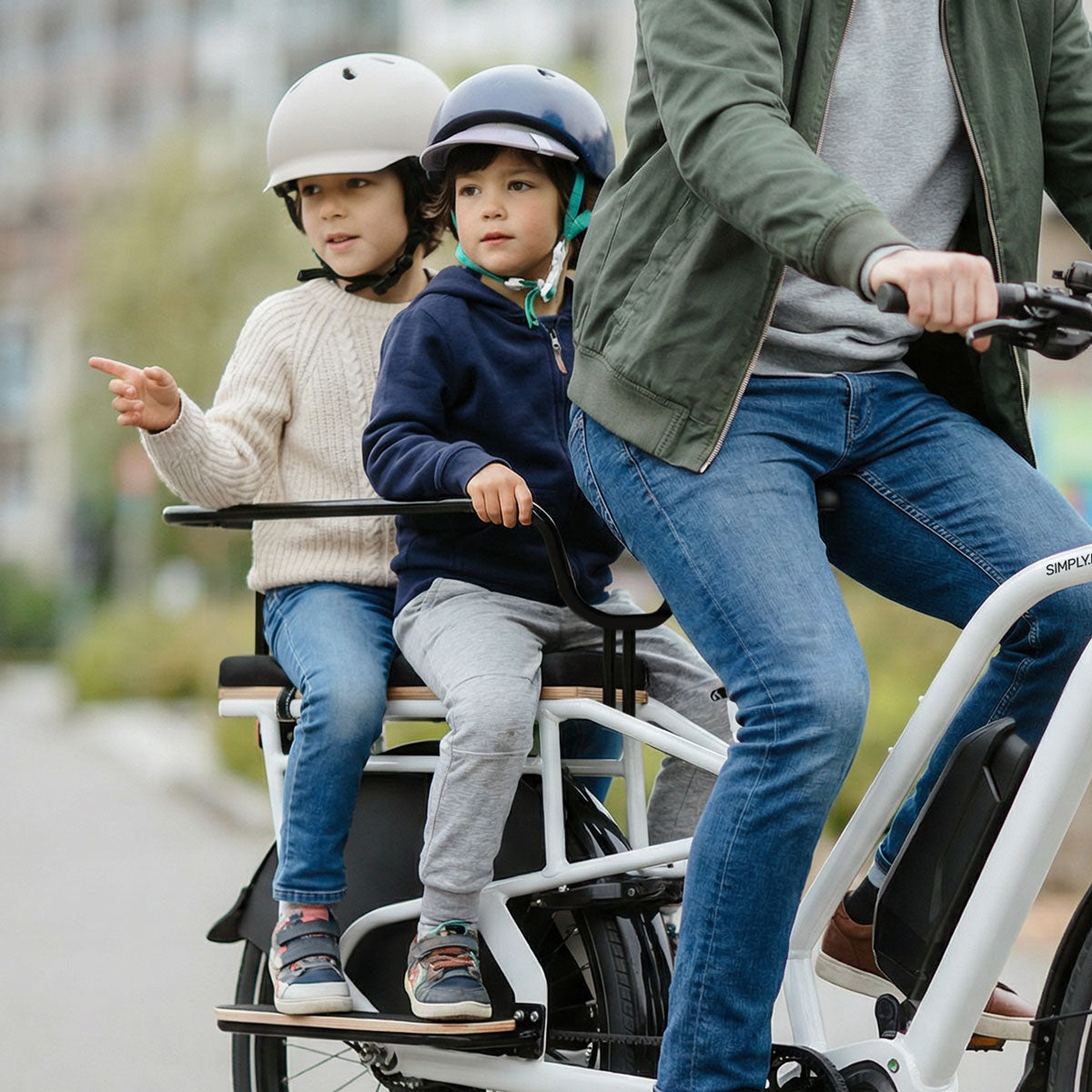 Frau fährt mit zwei Kindern auf dem weißen Simply.Lift EP6 E-Lastenrad.