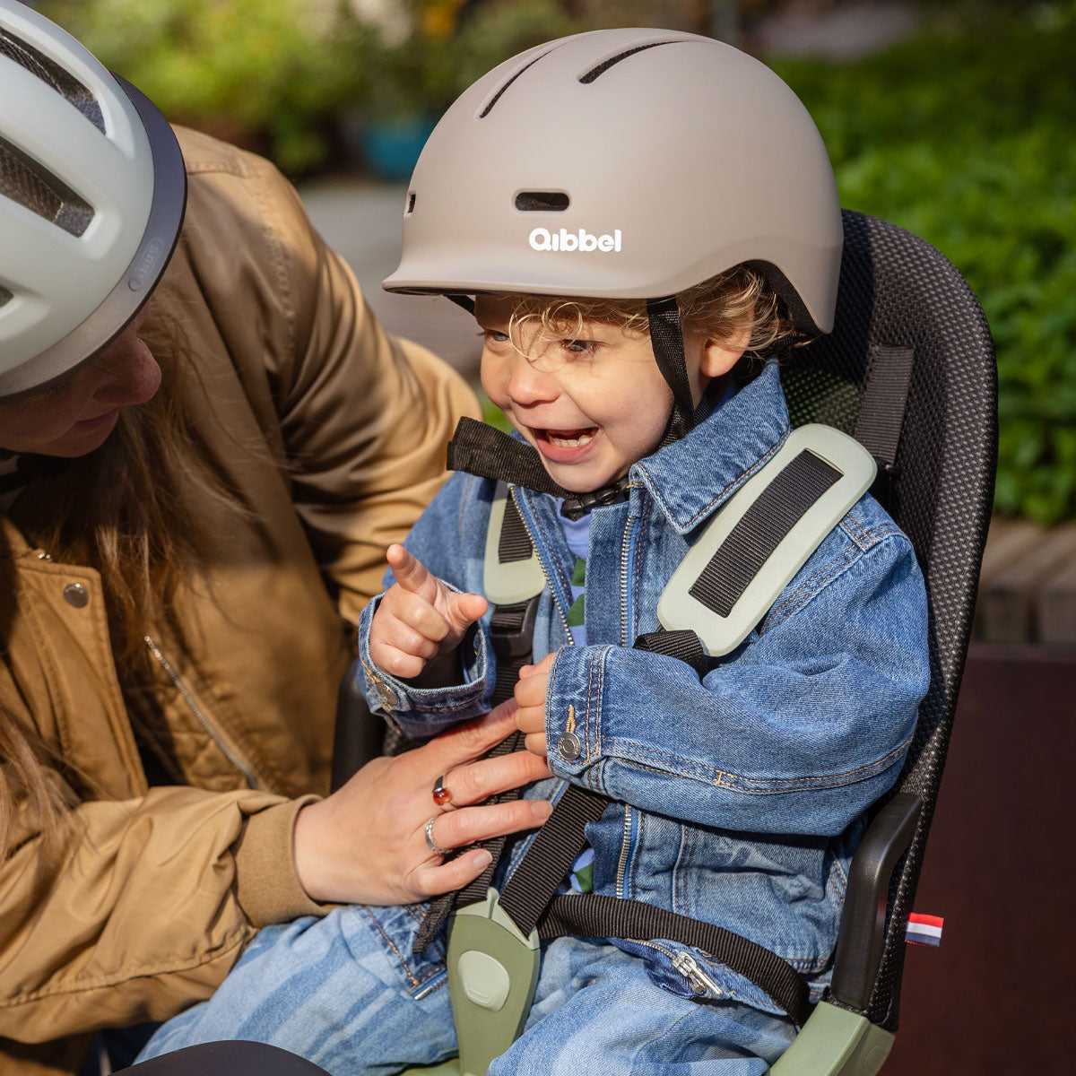 Kind sitzt angeschnallt und mit Helm im Qibbel Air Fahrradkindersitz