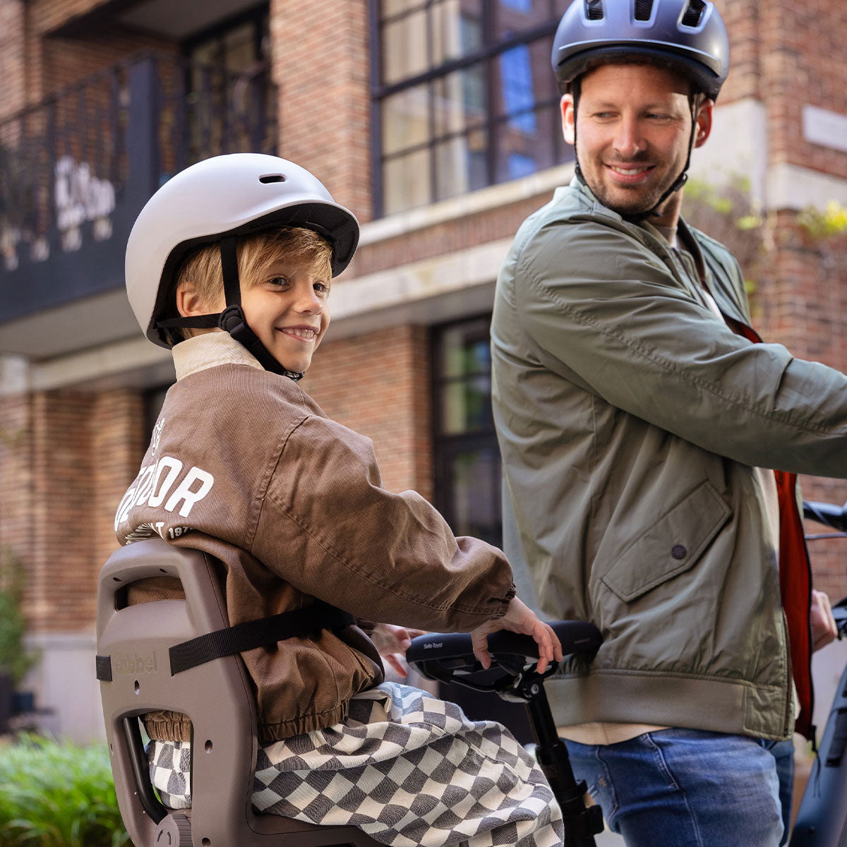 Größeres Kind sitzt mit Helm im Qibbel Junior 6+ Kindersitz auf einem E-Lastenrad