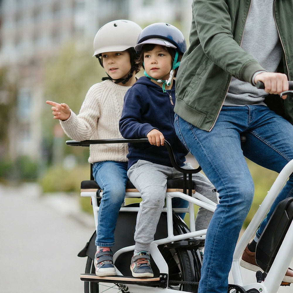 Zwei Kinder sitzen auf dem gepolsterten Sitzpolster des Simply.Lift E-Lastenrads