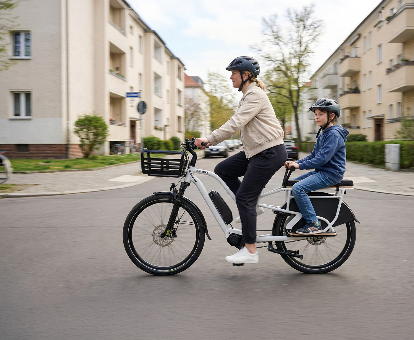 Eine Frau fährt ein Simply.Lift EP6 Longtail E-Lastenrad mit einem Kind auf dem verlängerten Gepäckträger und Kindergriff durch ein Wohngebiet.