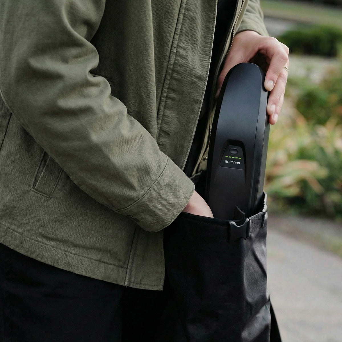 Nahaufnahme einer Person, die den Shimano Akku des Simply.Lift EP6 Longtail E-Lastenrads in eine Transporttasche steckt.