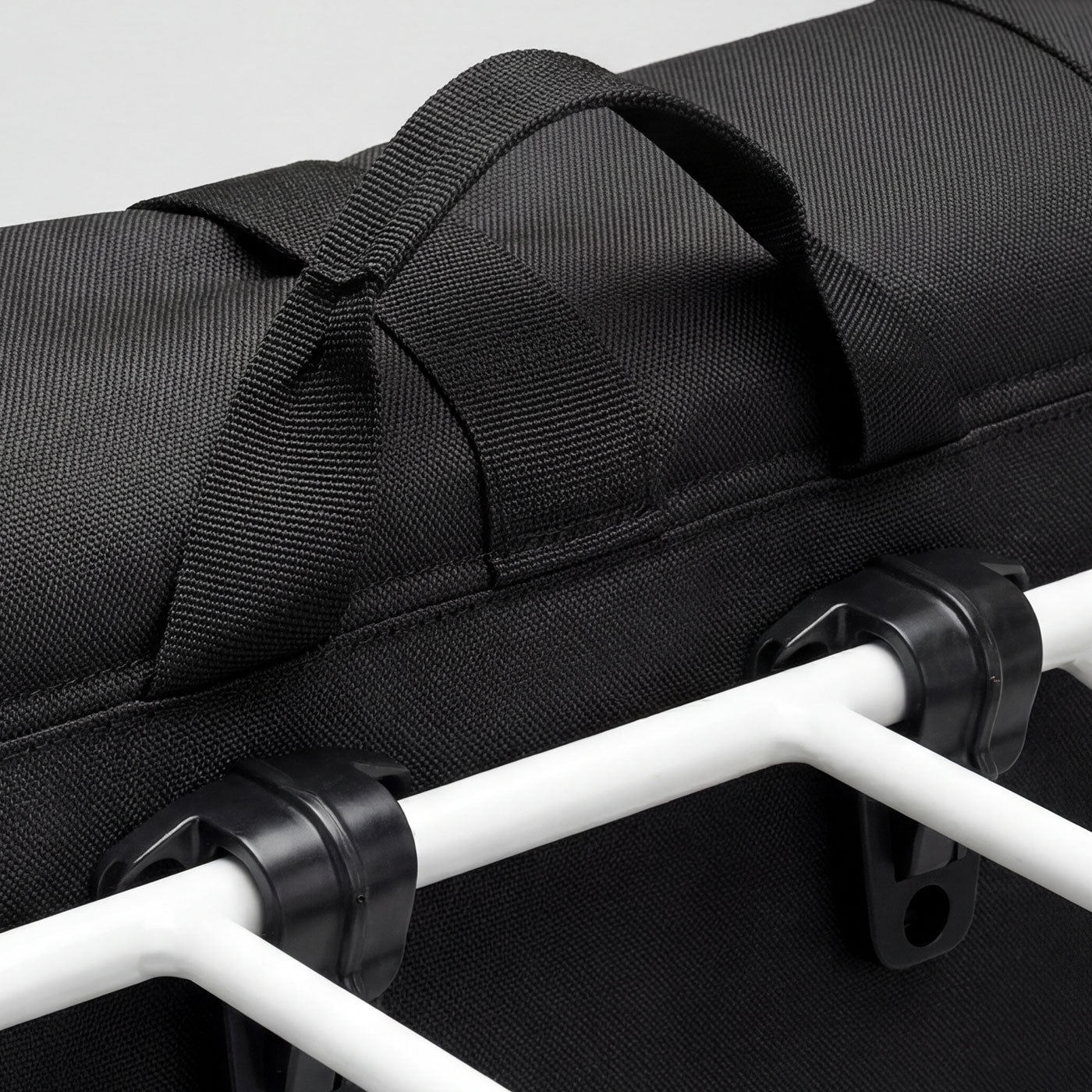 Schwarze Packtasche mit Klicksystem am weißen Gepäckträger des Simply.Lift EP6 E-Lastenrads.