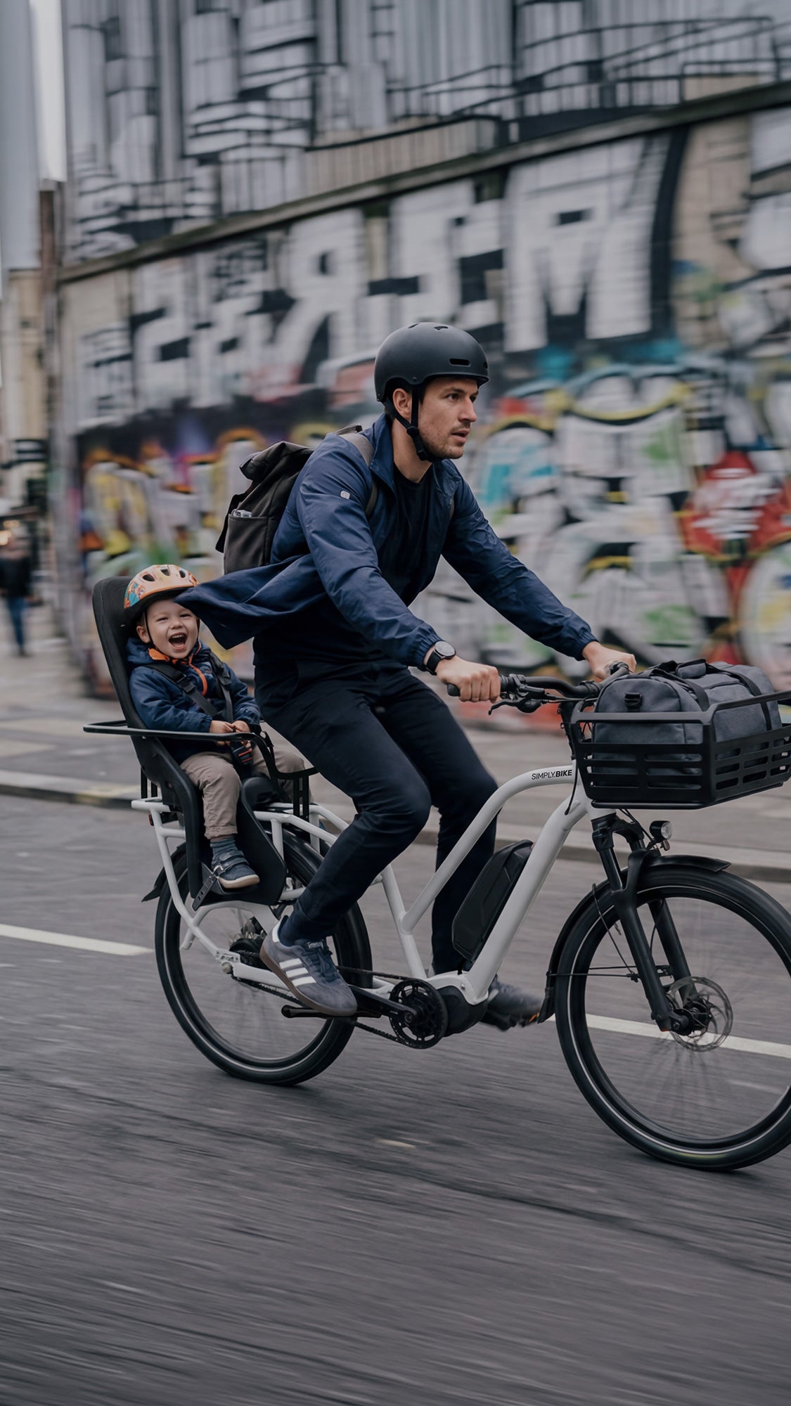 Simply.Lift EP6 Longtail E-Lastenrad mit einem Kind im rückseitigen Kindersitz und einer Tasche im Frontkorb.