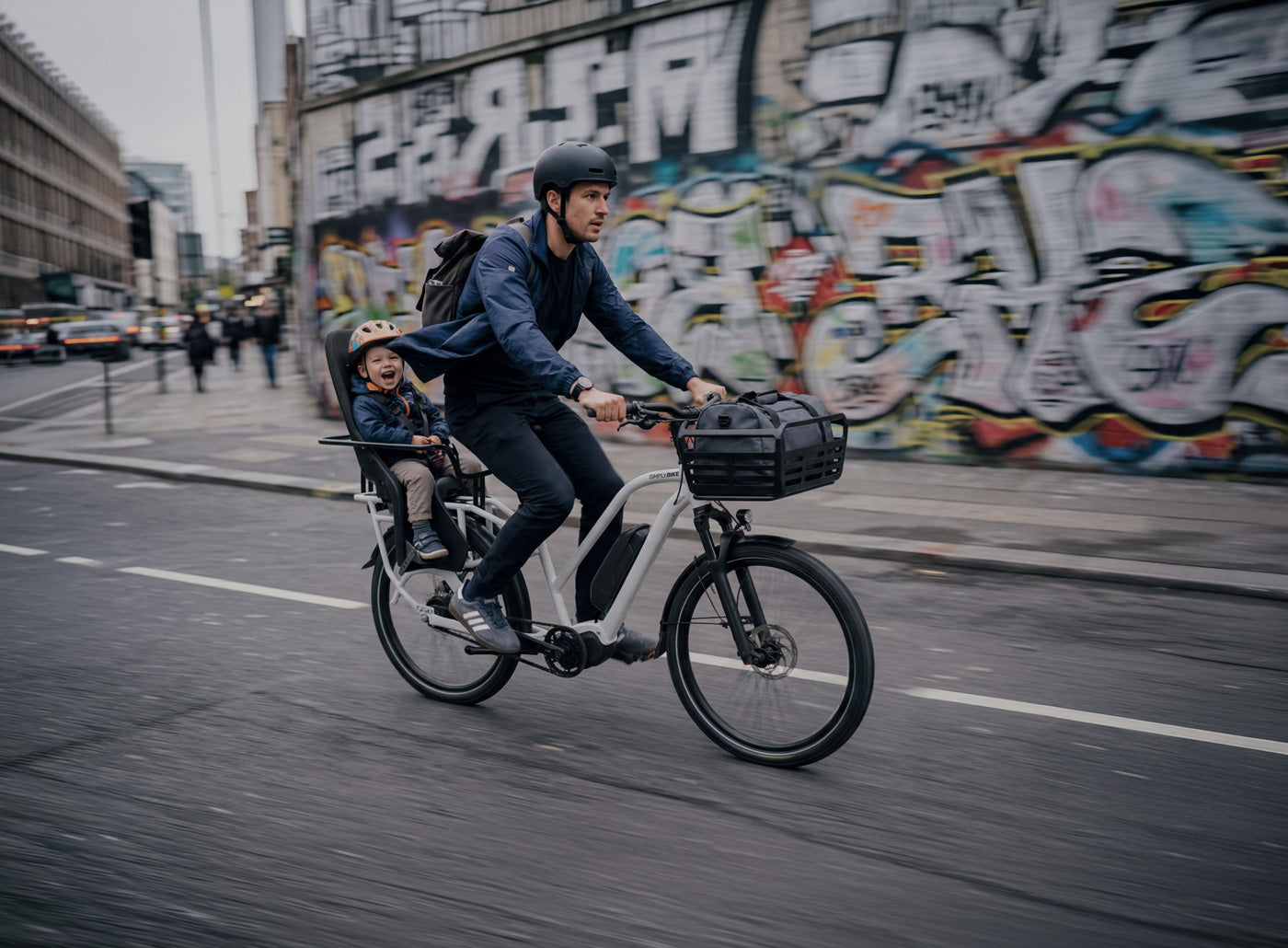 Simply.Lift EP6 Longtail E-Lastenrad mit einem Kind im rückseitigen Kindersitz und einer Tasche im Frontkorb.